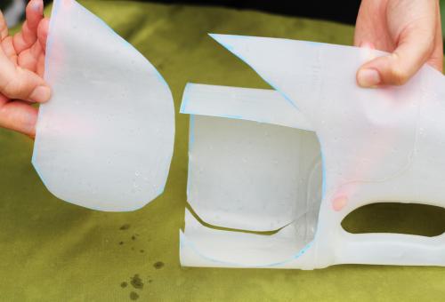 Two hands showing a milk carton where the top and bottom half have been separated